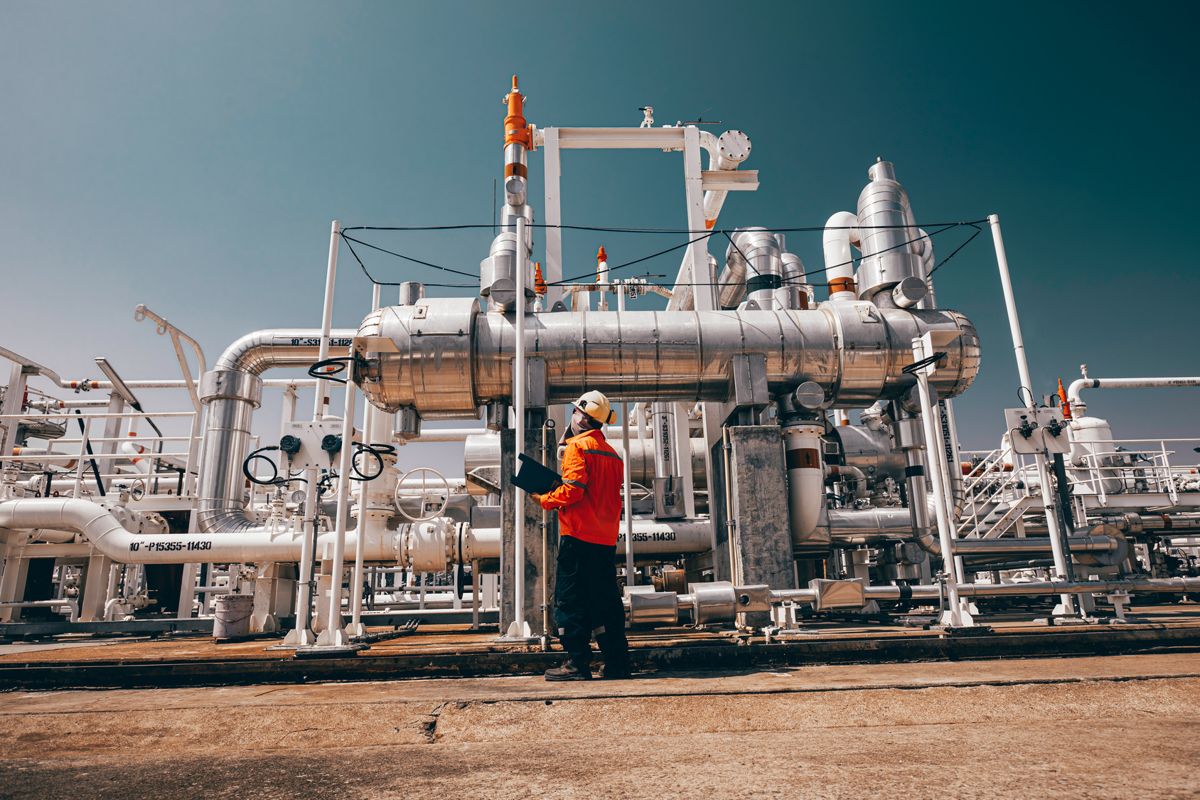 Engineer inspecting a shell-and-tube heat exchanger at a refinery